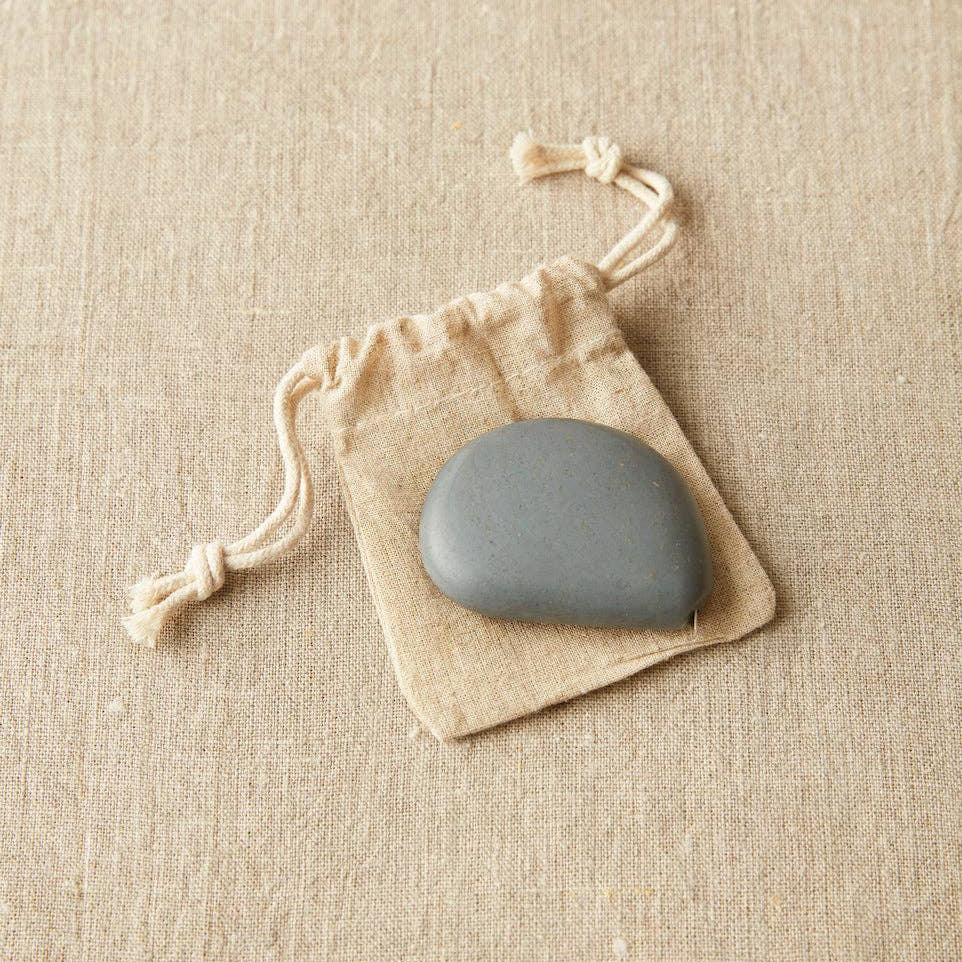 Gray stone on a beige drawstring bag against a beige fabric background