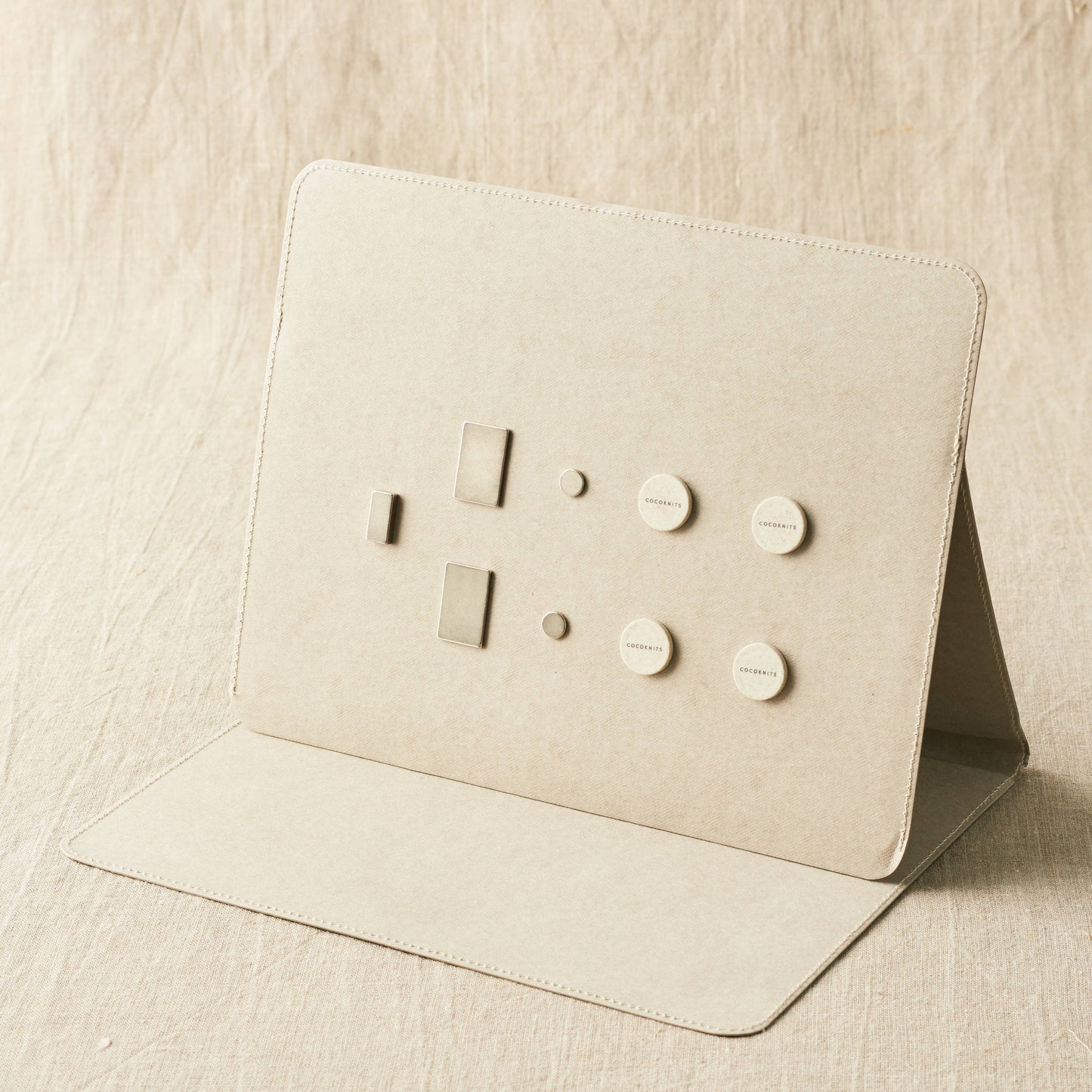 Beige leather cardholder with embossed designs on a beige fabric background