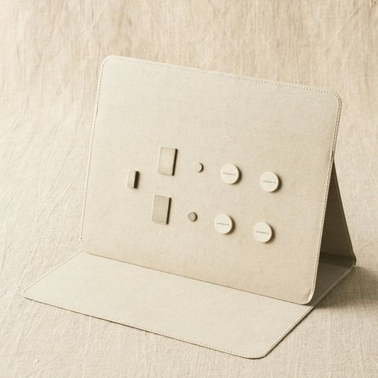 Beige leather cardholder with embossed designs on a beige fabric background