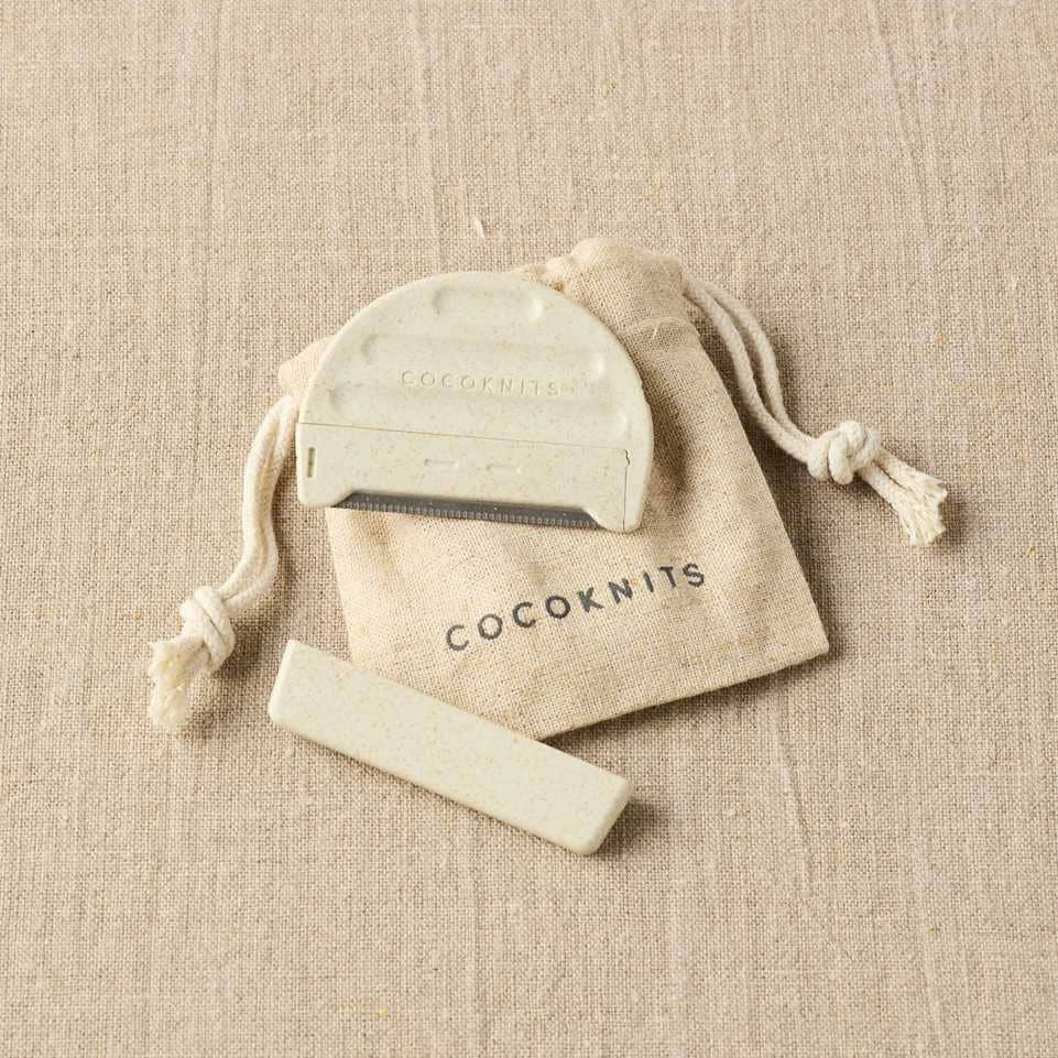 Cocoknits knitting needle case with a green tool on a beige fabric background