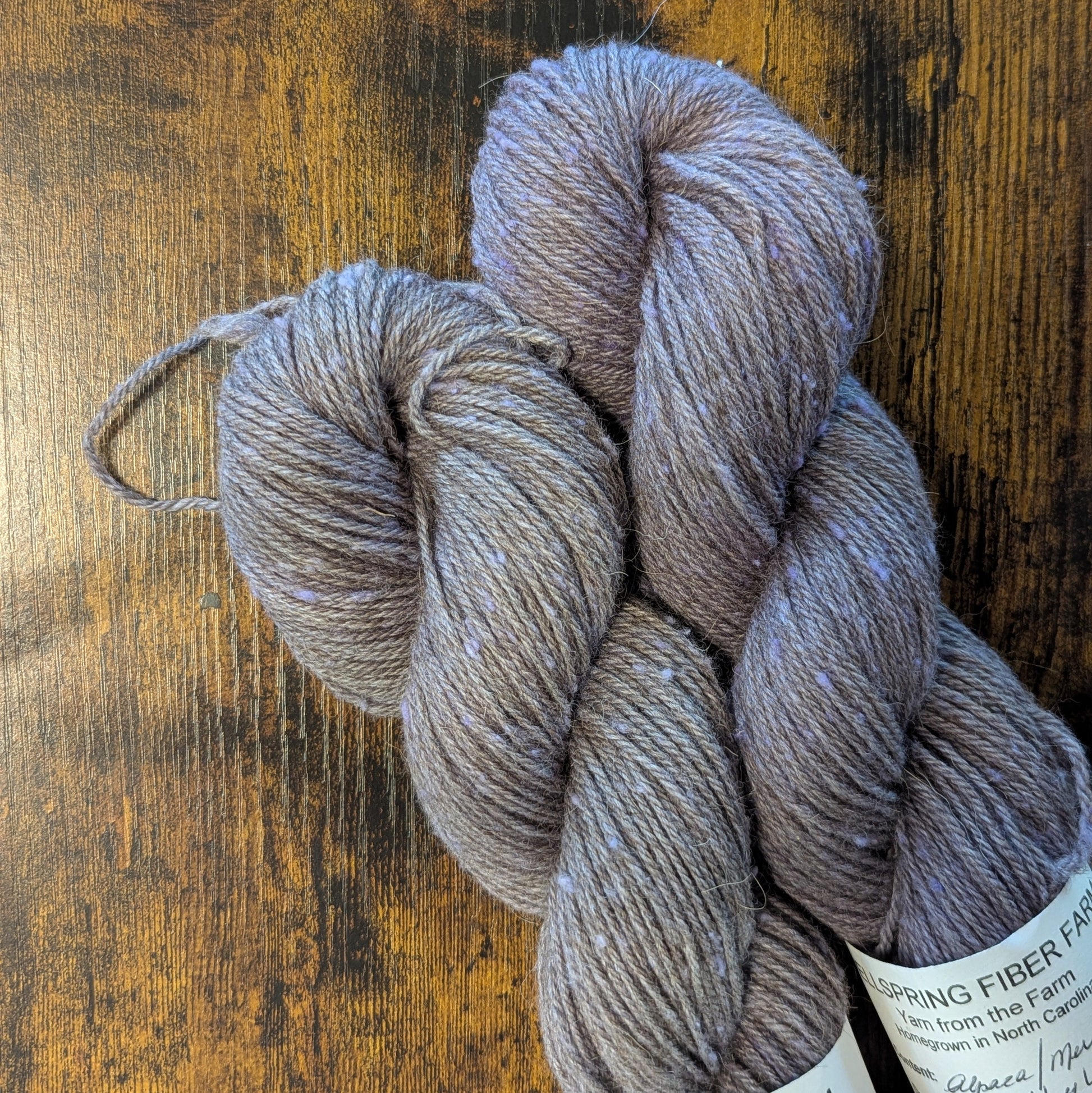 Three skeins of yarn on a wooden surface with 