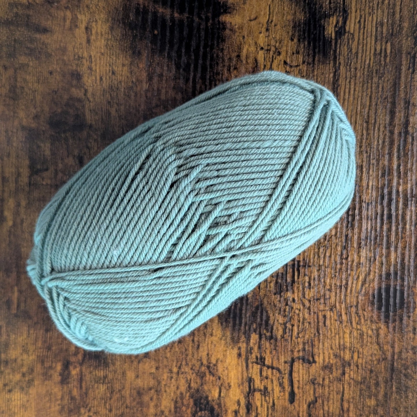 Teal skein of yarn on a wooden surface