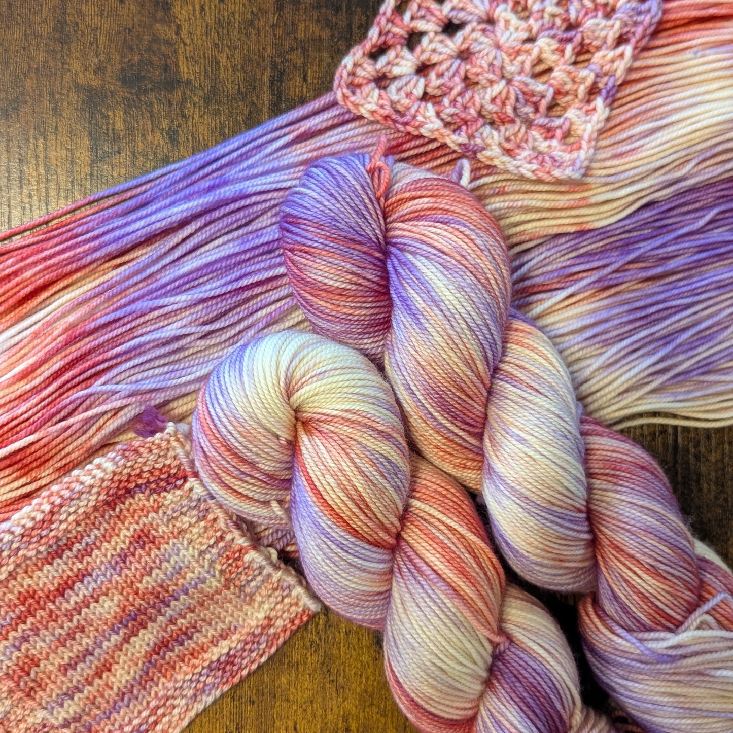 Colorful skein of yarn with a knitted square on a wooden surface