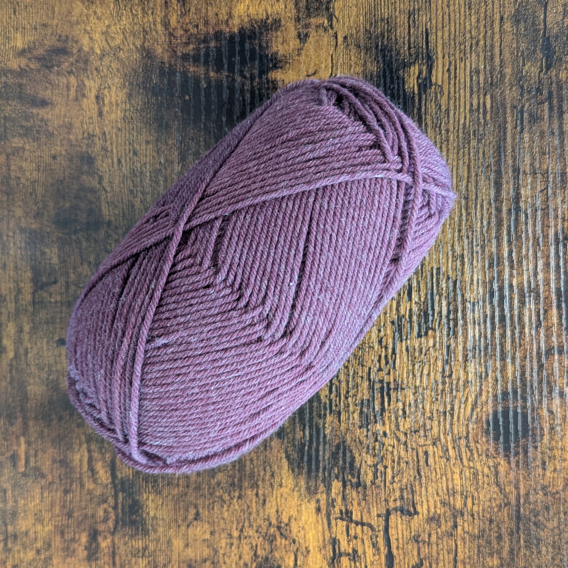 Purple skein of yarn on a wooden surface