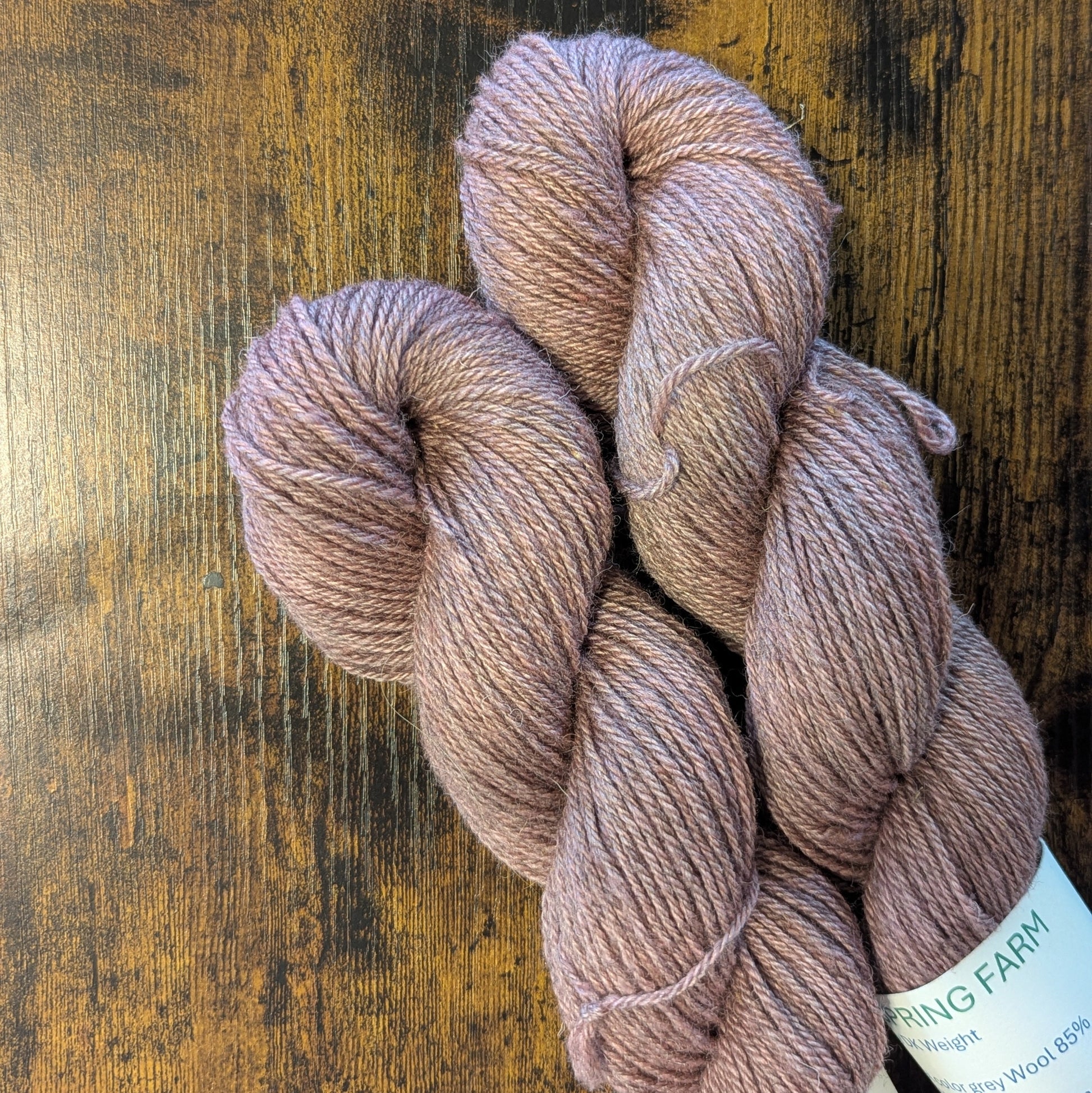 Three skeins of pink yarn on a wooden surface