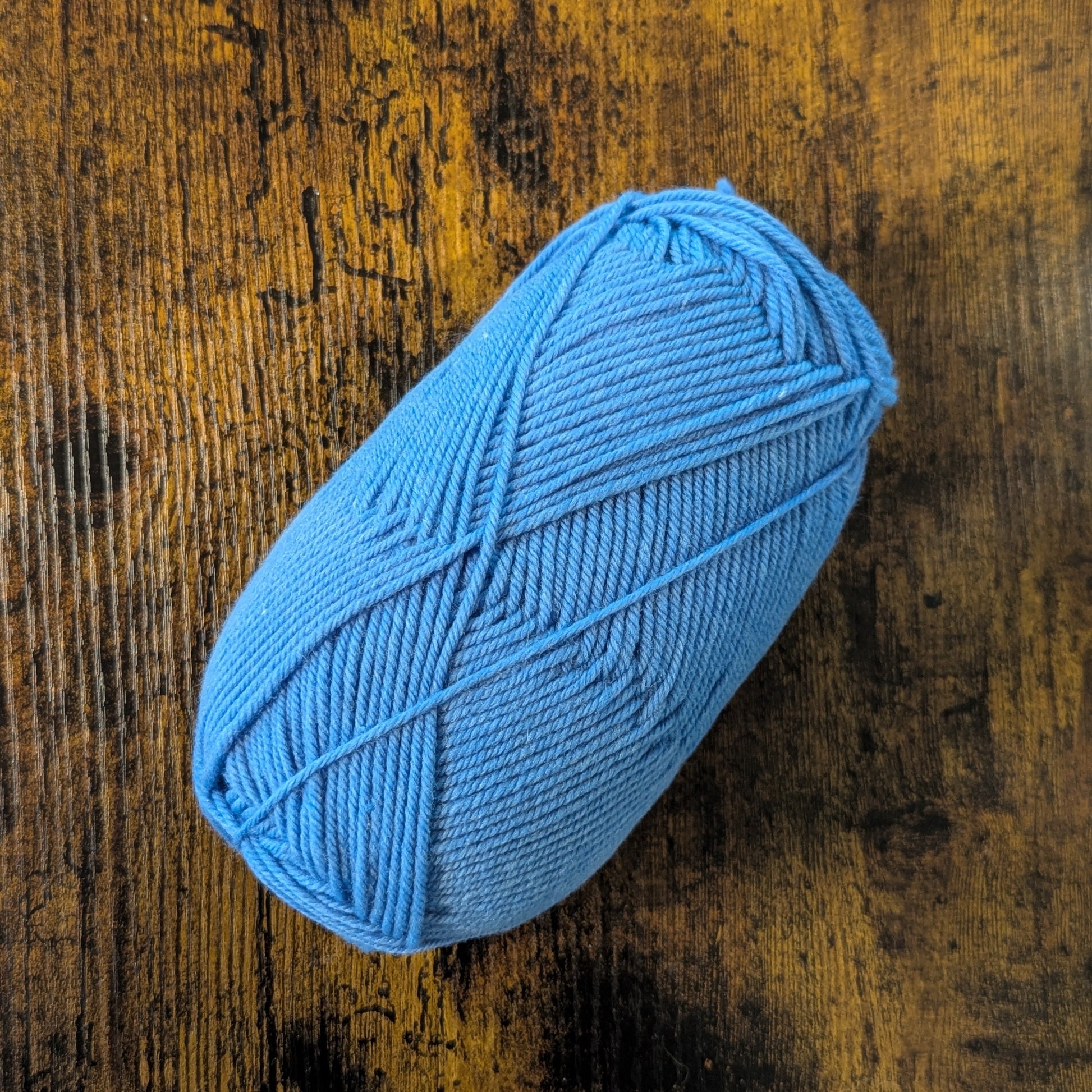 Blue yarn ball on a textured wooden surface