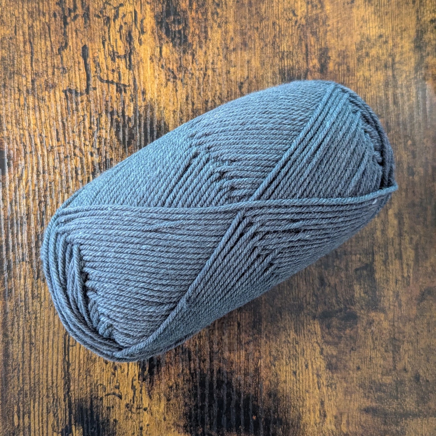 Grey skein of yarn on a wooden surface