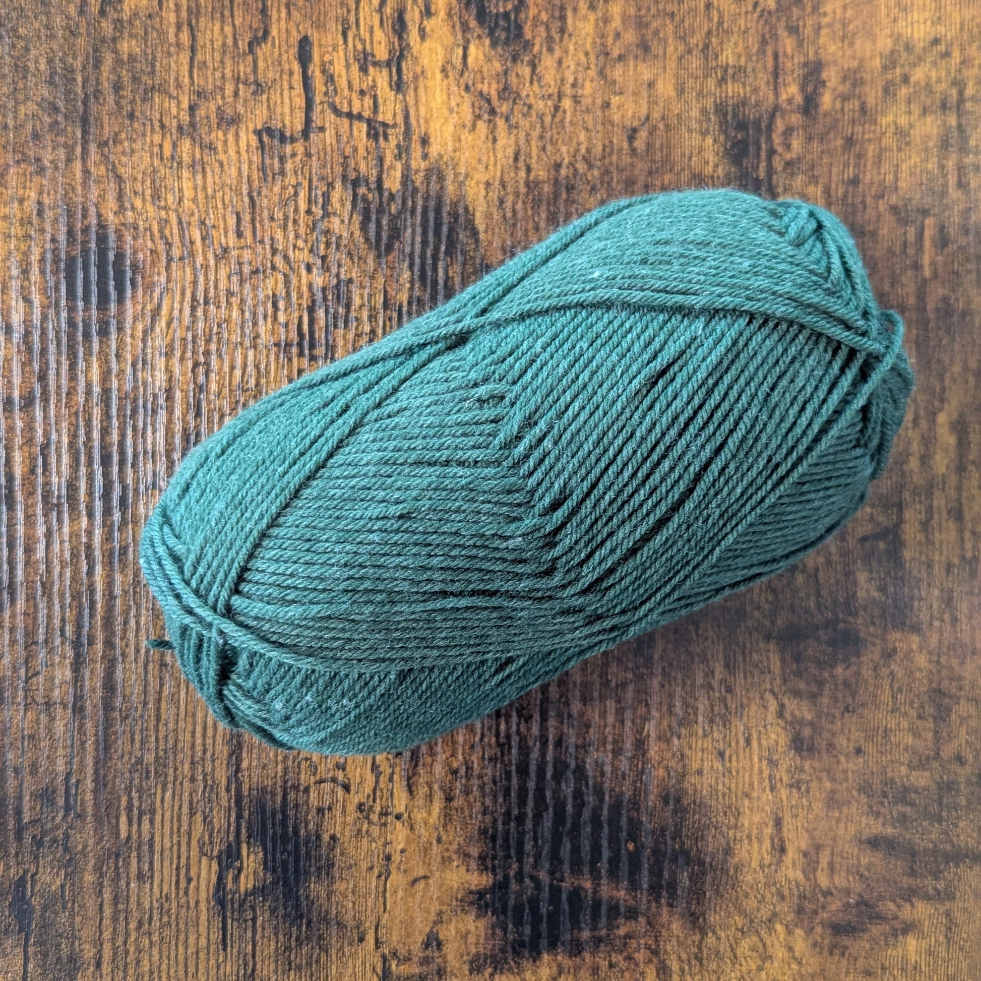 Dark Green skein of yarn on a wooden surface