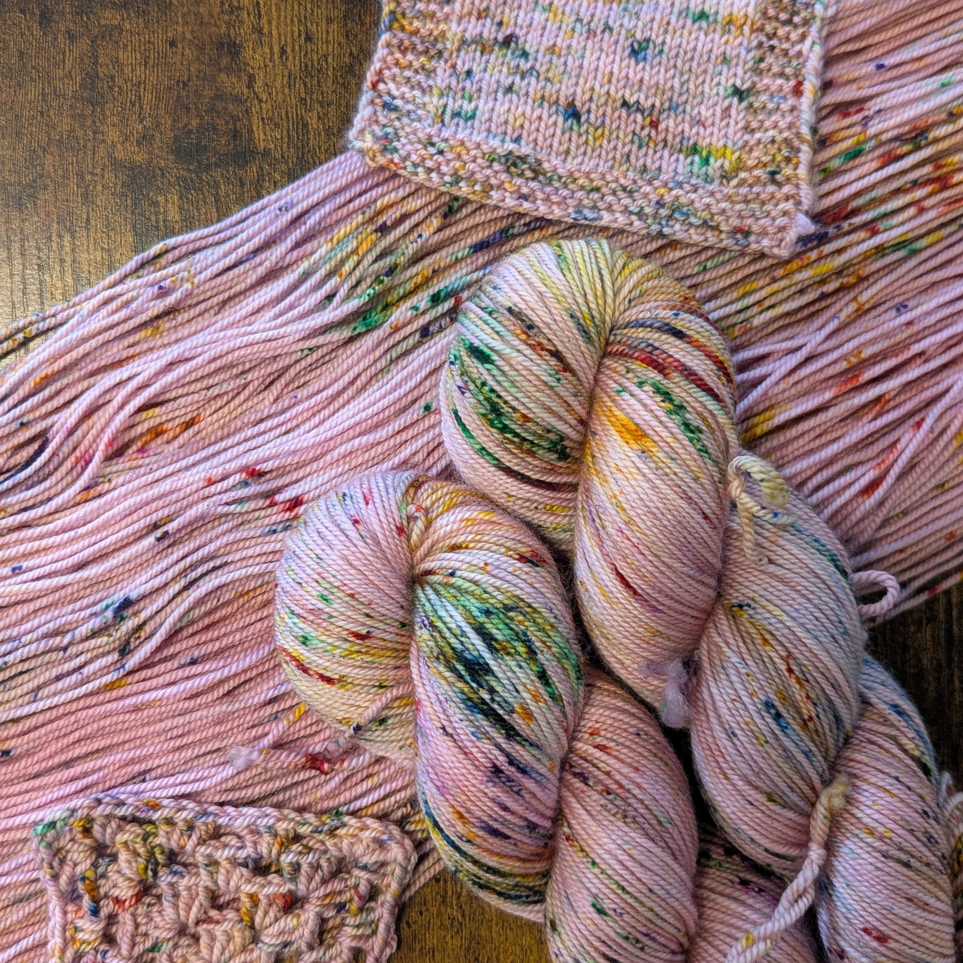Multicolored yarn skeins with knitted swatches on a wooden surface