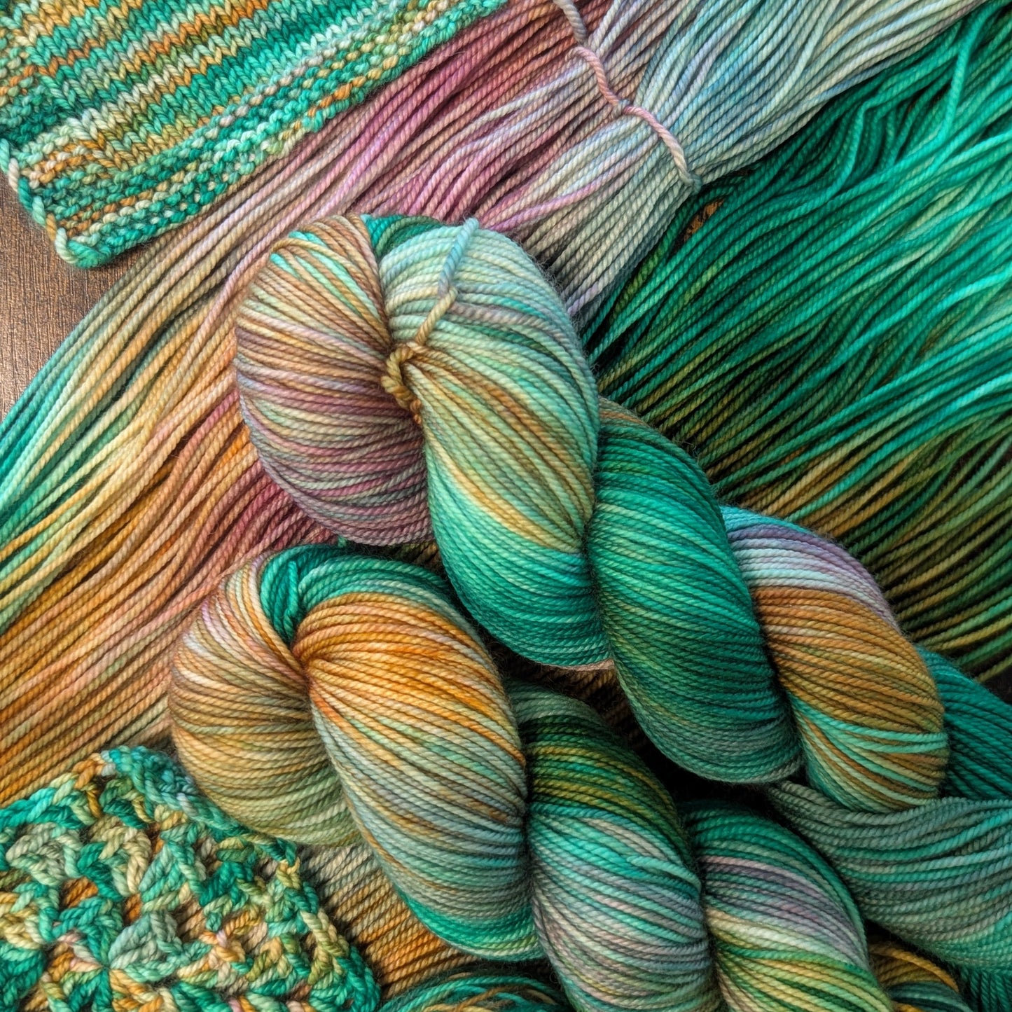 Colorful yarn skeins and a knitted item on a wooden surface