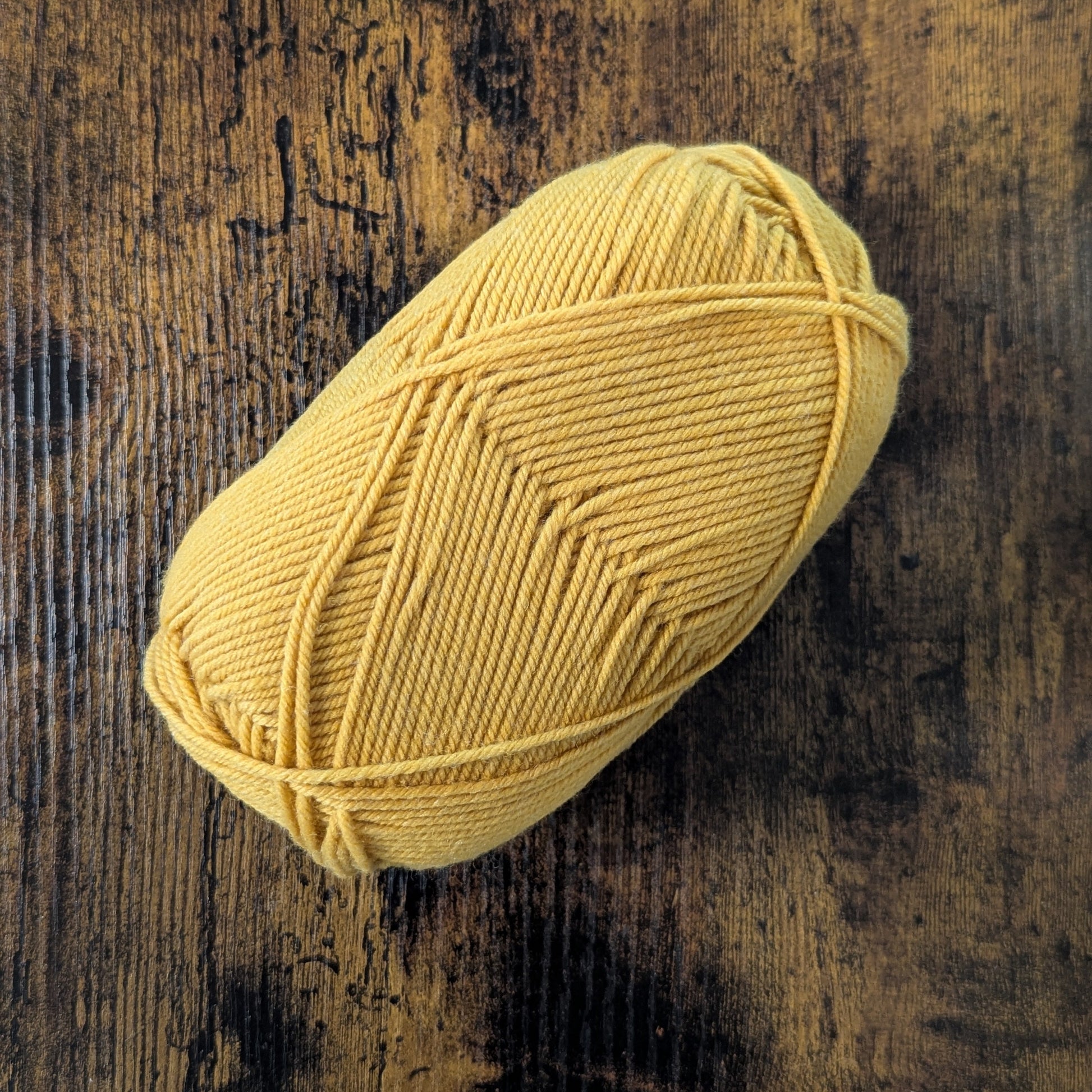 Yellow yarn ball on a textured wooden surface
